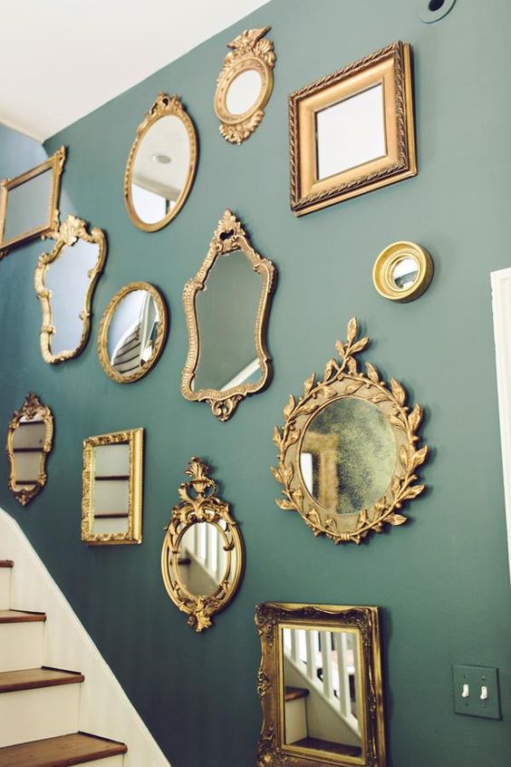 a green wall over the staircase and a gallery wall of mirrors, with chic and refined gold frames is a cool and catchy addition to the space
