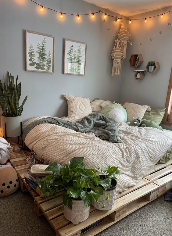 a grey boho bedroom with a pallet bed and neutral bedding, potted plants, hexagon shelves and macrame hangings plus lights