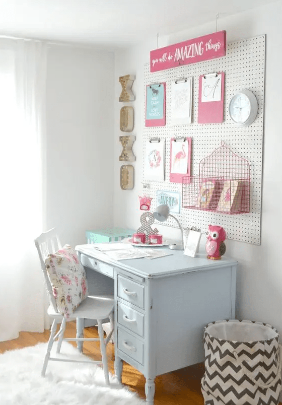a kid's space with a pale blue desk, a pegboard with decor and a clock, a chair with a vintage floral pillow