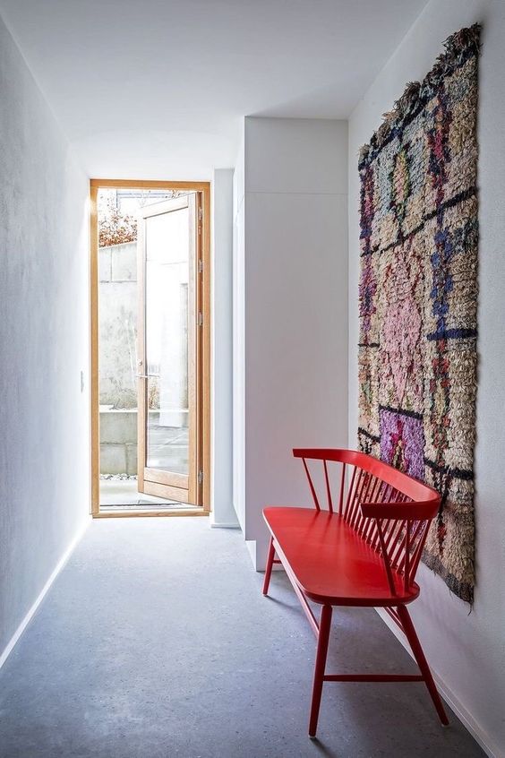 a laconic entryway with a colorful boho rug on the floor and a bold red vintage bench is amazing, it's boho but absolutely uncluttered