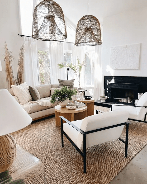 a lovely neutral living room with a fireplace, neutral seating furniture, a jute rug, wooden coffee tables, woven pendant lamps and some decor
