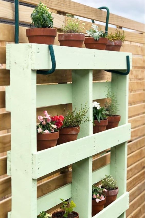 a mint green pallet garden as a planter holder, attached to the wall with huge hooks is a cool idea for a cottage or rustic space