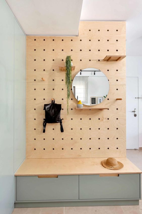 a modern and sleek entryway with a pegboard with hooks and shelves and a built-in storage unit with drawers is very cool
