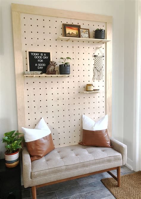 a modern entryway done with an upholstered bench, a pegboard with shelves and decor and some potted plants is amazing