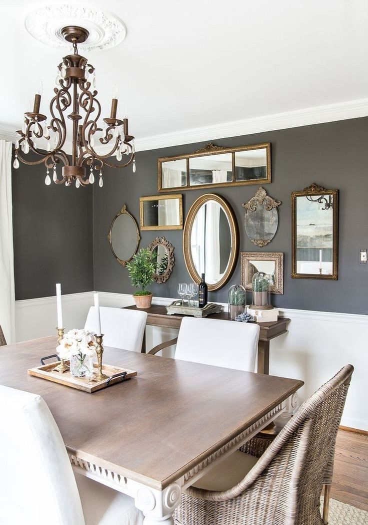 a modern farmhouse dining room with grey walls and white paneling, a stained console, a table and wicker chairs, a gallery wall of mirrors in chic frames