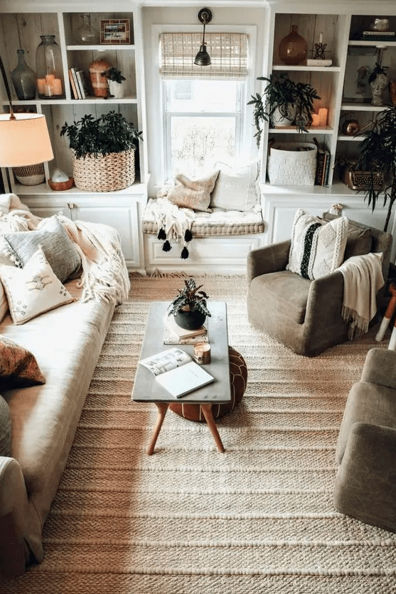 a modern farmhouse living room with built-in storage units, a neutral sofa and grey chairs, a jute rug, a coffee table and some lovely decor
