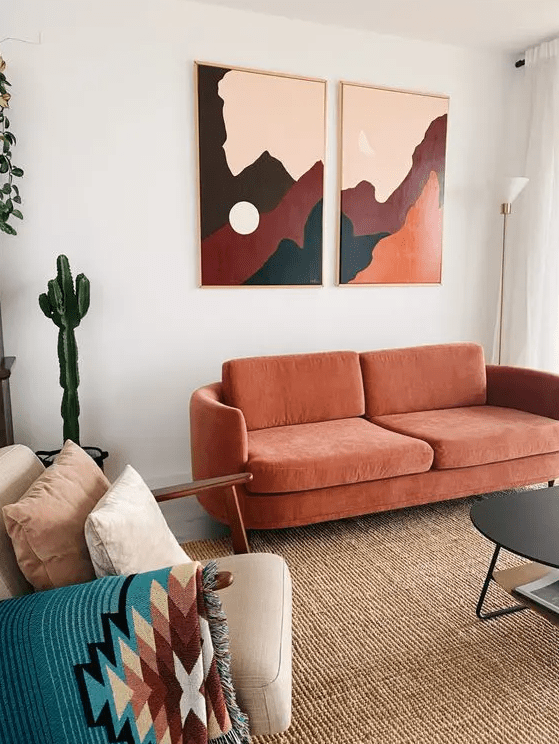 a modern living room with a jute rug, a rust sofa, a neutral chair with pillows, artwork and a black coffee table