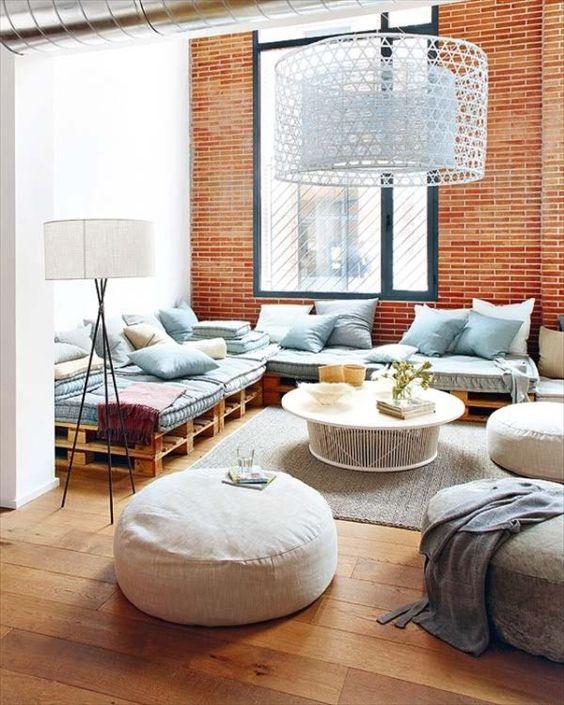 a modern living room with a pallet sofa, some poufs and ottomans, a coffee table and lots of blue pillows