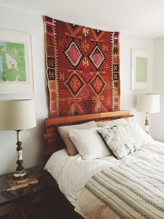 a neutral bedroom with a bold boho rug for a touch of color, a bed with neutral bedding, nightstands and table lamps