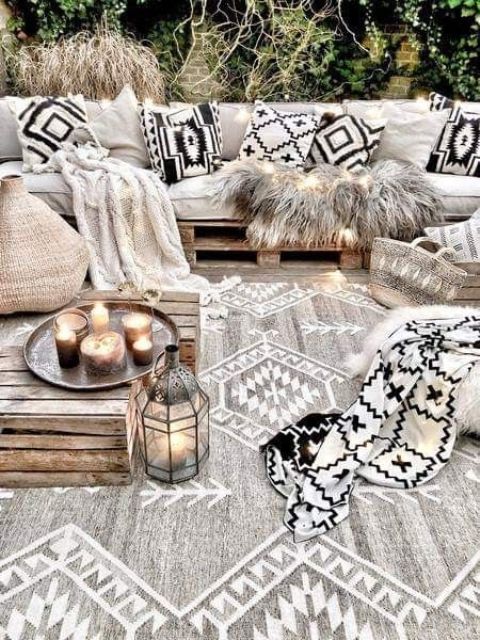 a neutral boho terrace with a pallet sofa, lots of boho pillows, a pallet table and some candles and lanterns