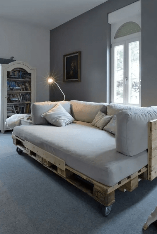 a pallet daybed with a back, casters and a comfy matress and pillows to make napping here comfy