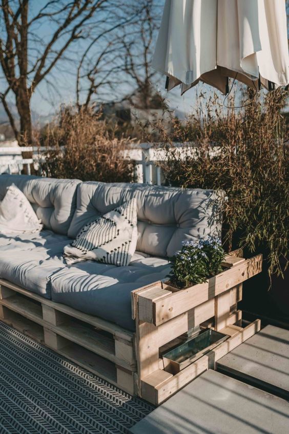 a pallet sofa with pillows is a cool idea for many terraces and balconies and you can DIY one
