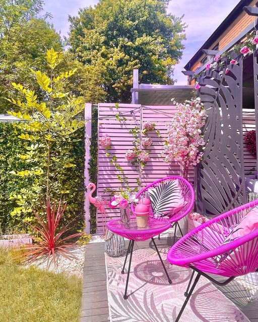 a pink terrace with hot pink chairs and a table, a flamingo and some blooms is amazing