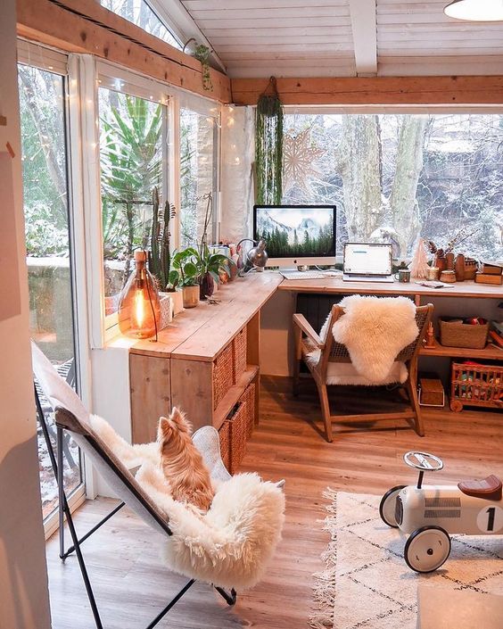 a pretty shed home office with glazed walls, a corner desk with a chair, potted plants, lots of books and a butterfly chair