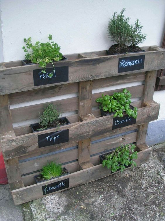 a reclaimed pallet garden with some planters with herbs and chalkboard stickers to mark the plants is a cool rustic decor idea