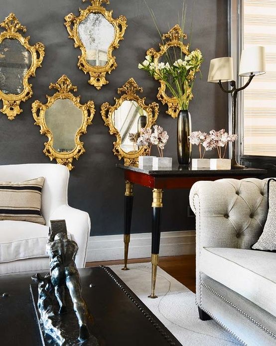 a refined living room with neutral seating furniture, a coffee table, a stained table, a gallery wall of matching mirrors in gorgeous gold frames