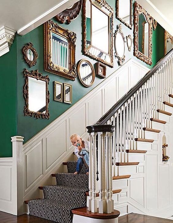 a refined space with a green wall and white paneling, a gallery wall of mirrors in chic and refined gold frames