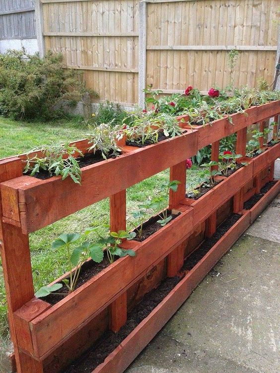 a rich-stained vertical pallet garden with greenery and blooms is a cool and practical idea for a rustic garden, you can make it yourself