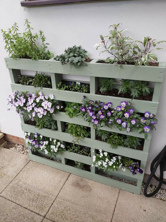 a sage green vertical garden of a pallet, with greenery and blooms, is a stylish idea for a Scandinavian space