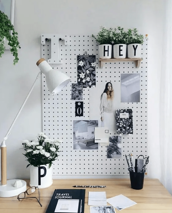 a small and pretty pegboard used as a memo board, with some photos, art and potted blooms, looks nice