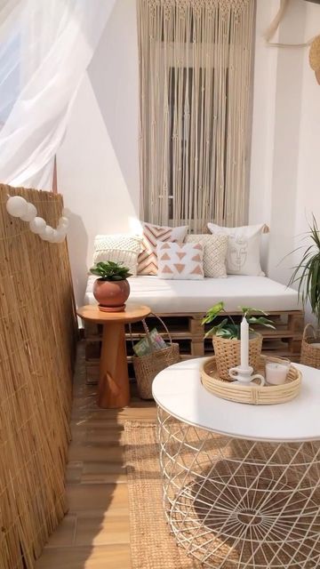 a small boho balcony with a pallet loveseat, a coffee table, potted plants and lights is amazing