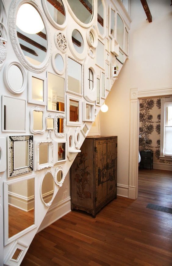 a staircase wall fully covered with mirrors in mismatching frames is a spectacular idea for a quirky and whimsical interior