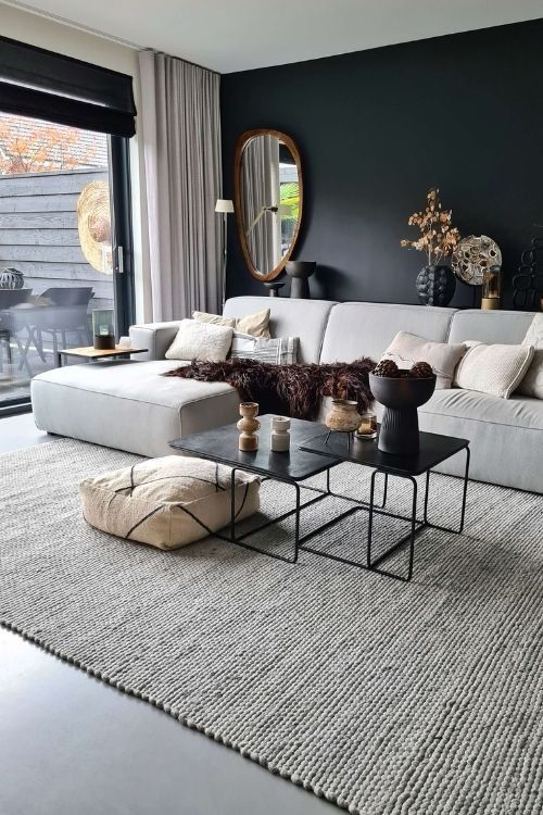 a stylish Scandinavian living room with a black accent wall, a neutral sofa and pillows, a jute rug, some catchy decor