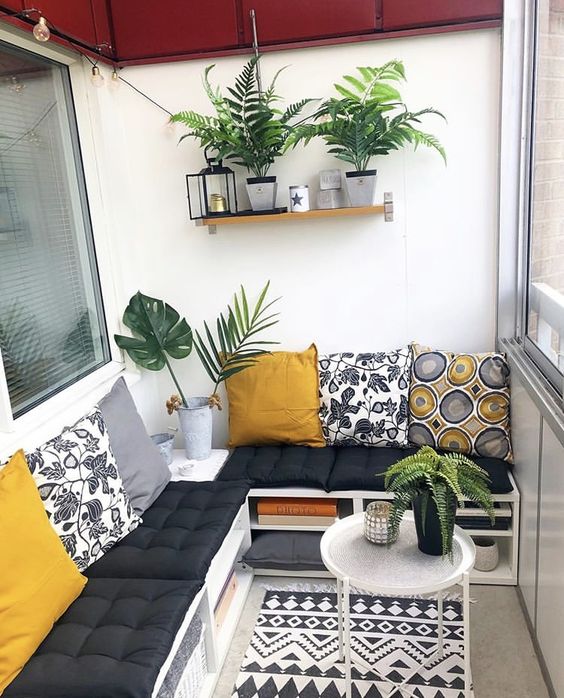 a stylish balcony with a pallet corner sofa and colorful pillows, potted plants and a printed boho rug is a lovely space
