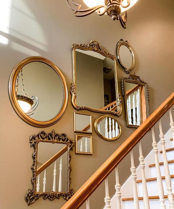 a tan wall over the stairs, with a gallery wall of mirrors in beautiful gold frames is a cool and chic solution for any space