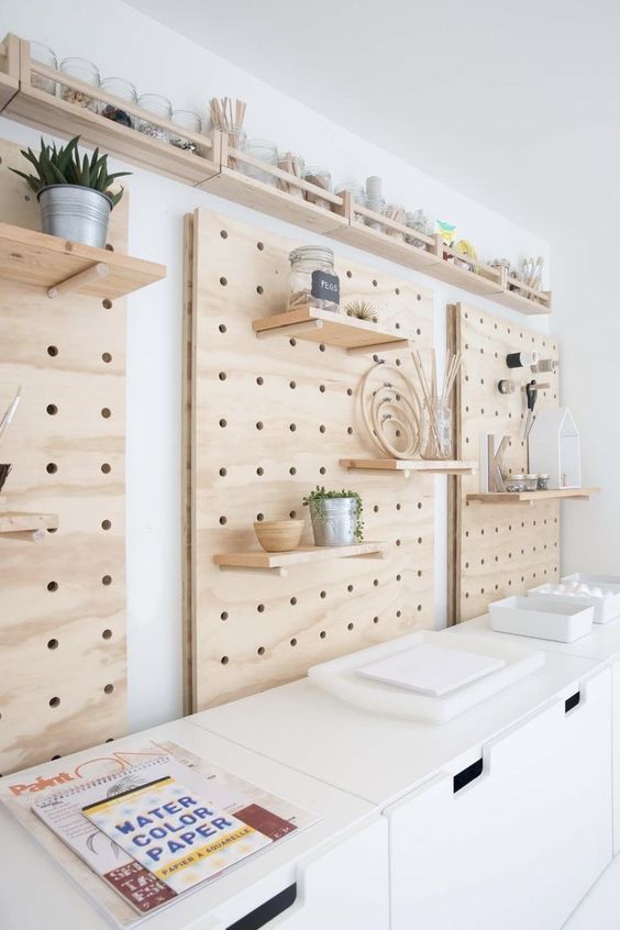 a trio of pegboard paired with large chests for storage, with open shelves and some decor, will fit a Scandinavian room