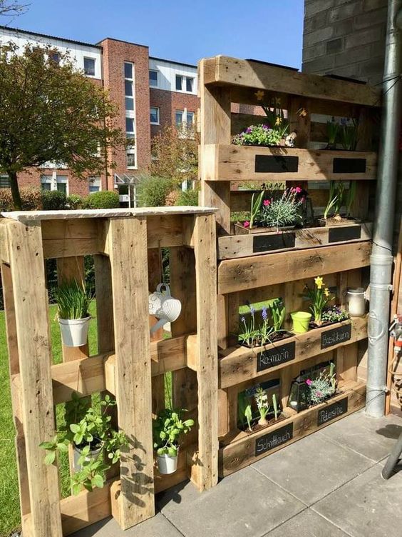 a vertical garden of pallets with various spring blooms is a nice privacy screen and decoration for a balcony