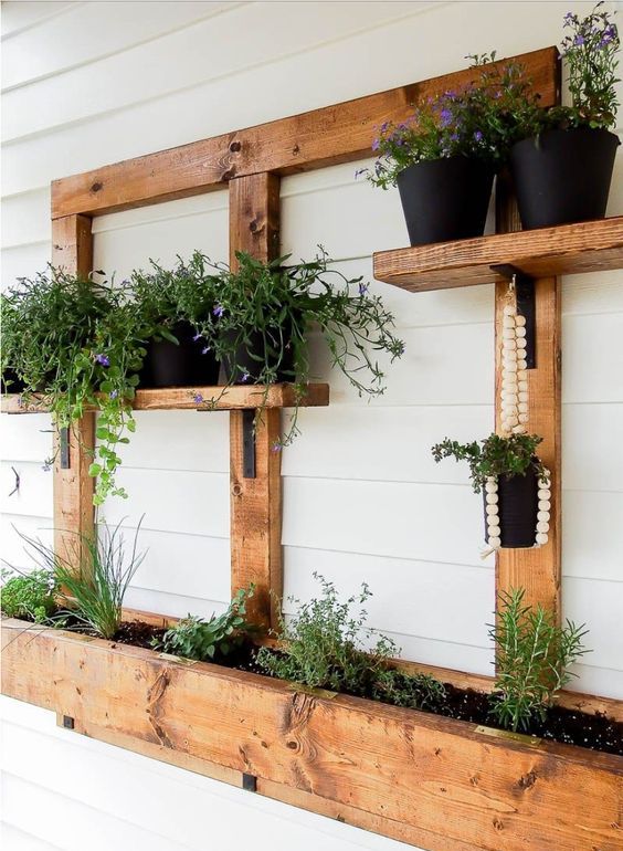a vertical wall garden built of pallets, with herbs planted and potted blooms and greenery is amazing for a rustic indoor or outdoor space