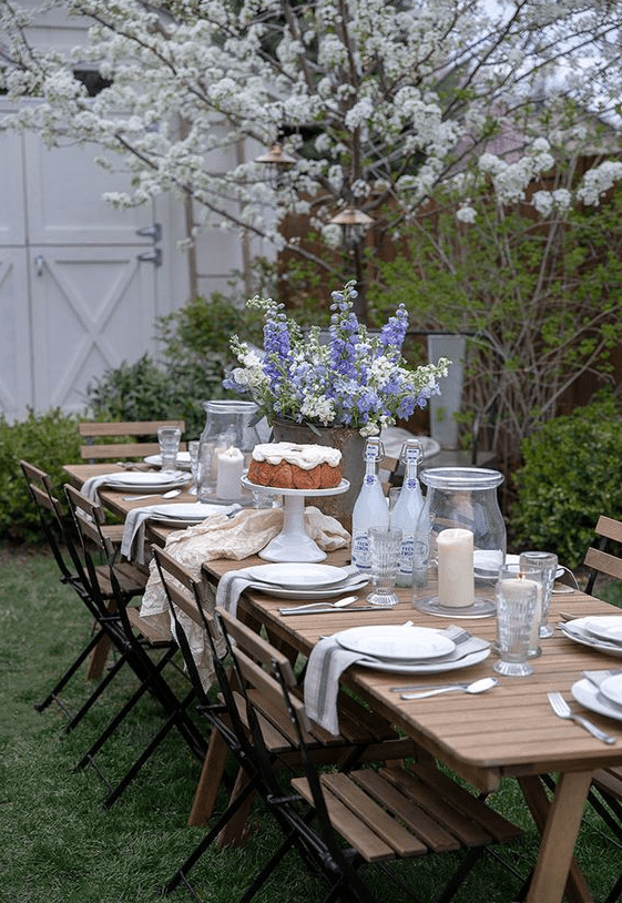 a welcoming dining zone with a wooden table and wooden and metal chairs, neutral linens and blooming trees around