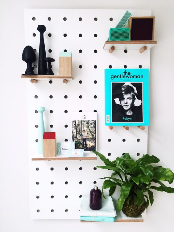 a white pegboard with shelves, decor and potted greenery is a cool decoration for any room, it can be aimed at various purposes