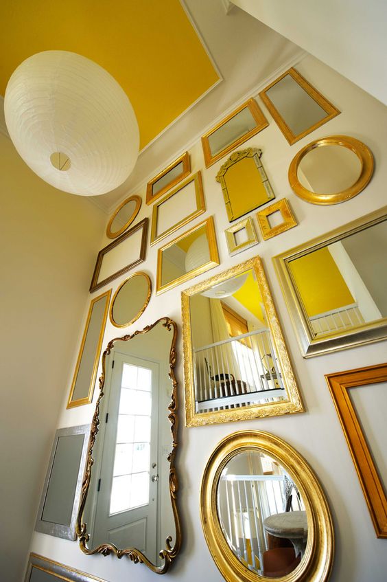 a white wall with a gallery wall of mirrors in various gold and brass frames to add a chic and sophisticated touch to the space
