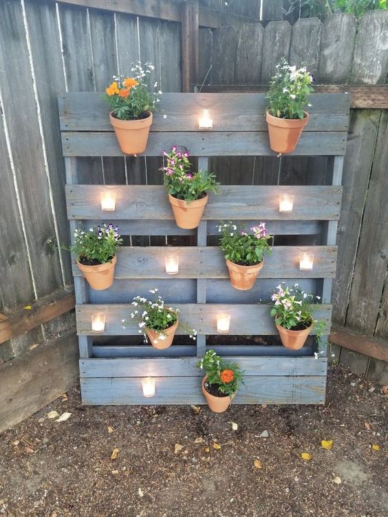 a whitewashed pallet garden with planters attached to it and some candleholders is a cool idea for any rustic outdoor space
