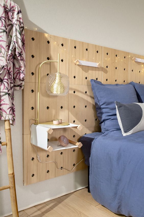 a wooden headboard made of pegboards, with lights, handles and a nightstand attached to it is a very creative idea for a Scandinavian space