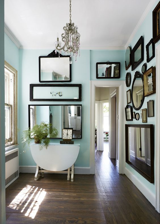an aqua-colored space with mirror gallery walls, a folding table and a vintage crystal chandelier