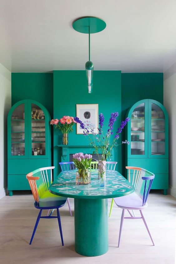 an emerald dining room with matching modern buffets, an emerald table and colorful benches and pendant lamps