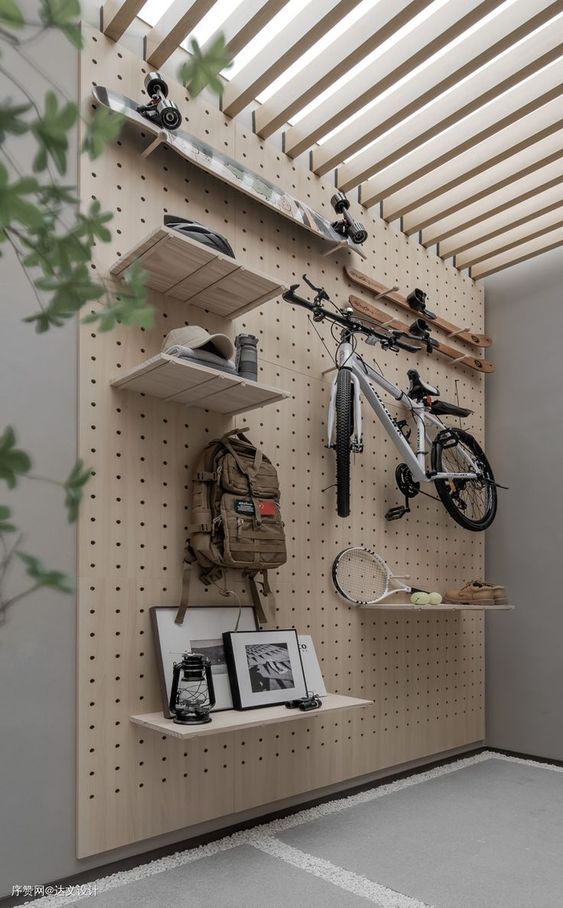 an entryway with a pegboard holding some shelves and hooks is a cool way to organize the space in a modern and stylish way