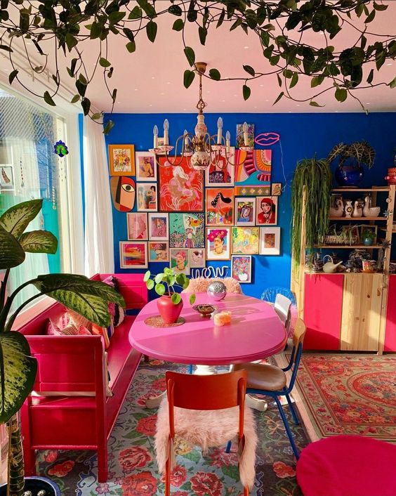 an extra bold dining room with a bold blue wall, a colorful gallery wall, a red bench, a pink table and a colorful buffet