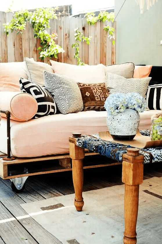 an outdoor pallet daybed on casters with a soft mattress and lots of colorful and printed pillows is heaven
