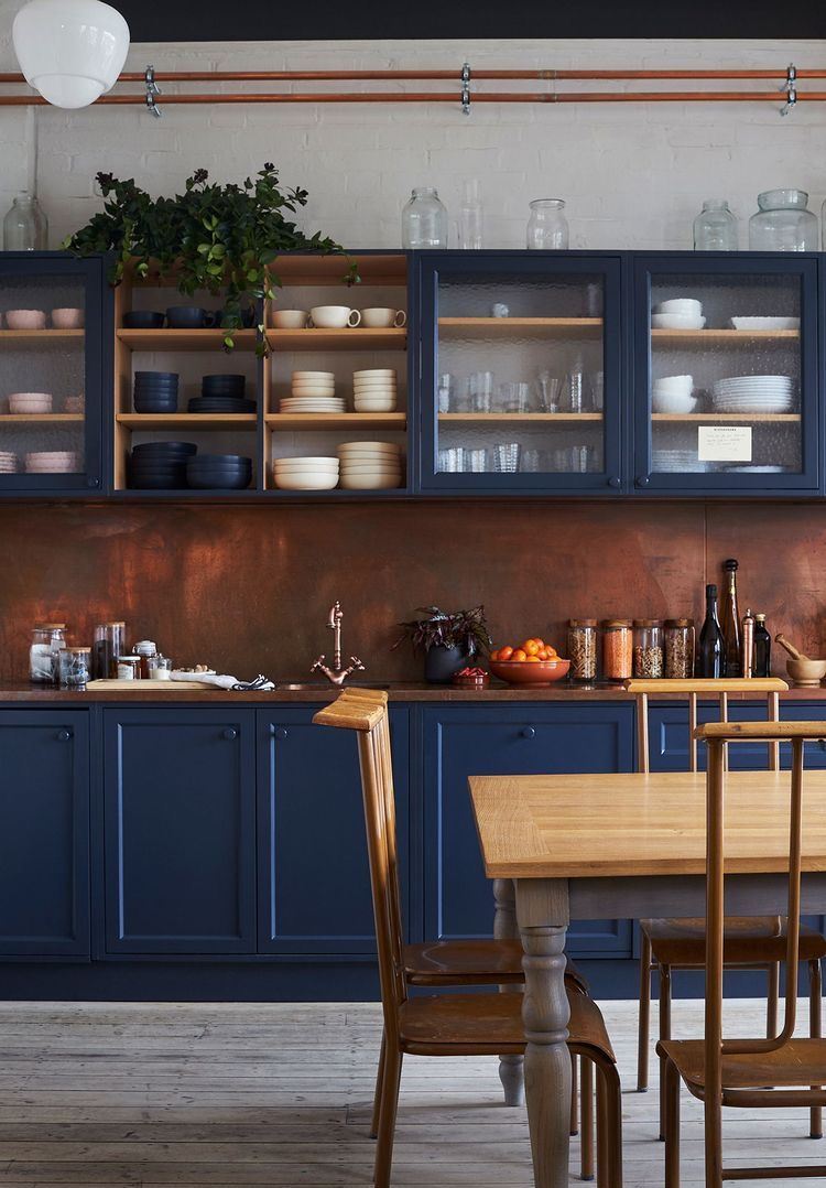 The beautiful space is made of navy cabinetry, a brown countertop and a copper backsplash that brings texture.