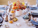 an elegant fall tablescape with neutral linens, bright blooms, fruits and veggies and a potted succulent plus porcelain