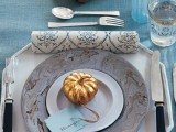 a chic fall tablescape with a blue tablecloth and a glass, a marble charger, faux gold pumpkins
