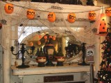 a messy Halloween mantel with spiderwebs, paper lanterns, black candleholders, lights and buntings