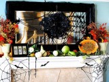 a Halloween mantel with spiderwebs, faux veggies and spiders, brigth fall blooms and leaves and a spider nest