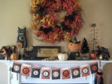 a vintage Halloween mantel with a faux leaf wreath, a vintage bunting, candles and vintage pumpkin toys
