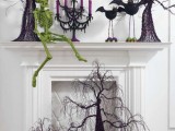a bold Halloween mantel with a neon green skeleton, scary purple trees, purple candles and funny bats plus a scary tree and skeletons in front of the fireplace
