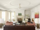an elegant feel is give to the living room with ceiling molding, elegant lamps, a crystal chandelier